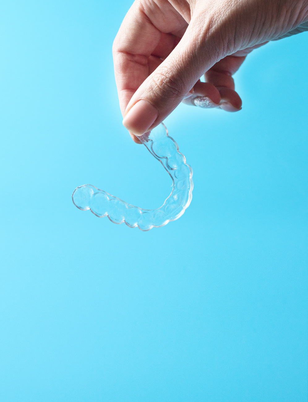 Hand holding Invisalign, the invisible braces aligner . Mobile orthodontic apparatus for the correction of teeth. Dental concept.